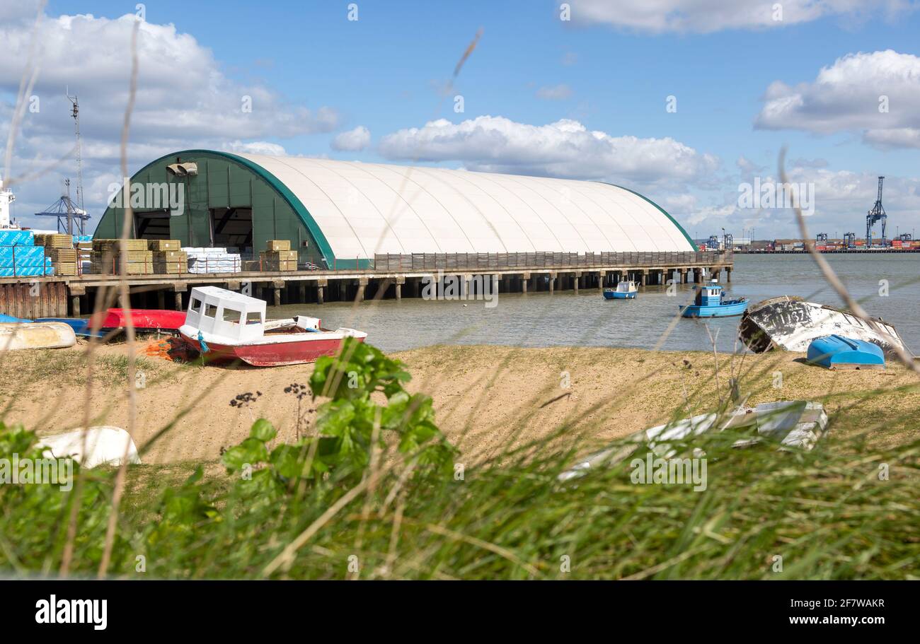 Warehouse dockyard building, small boats sandy beach foreground