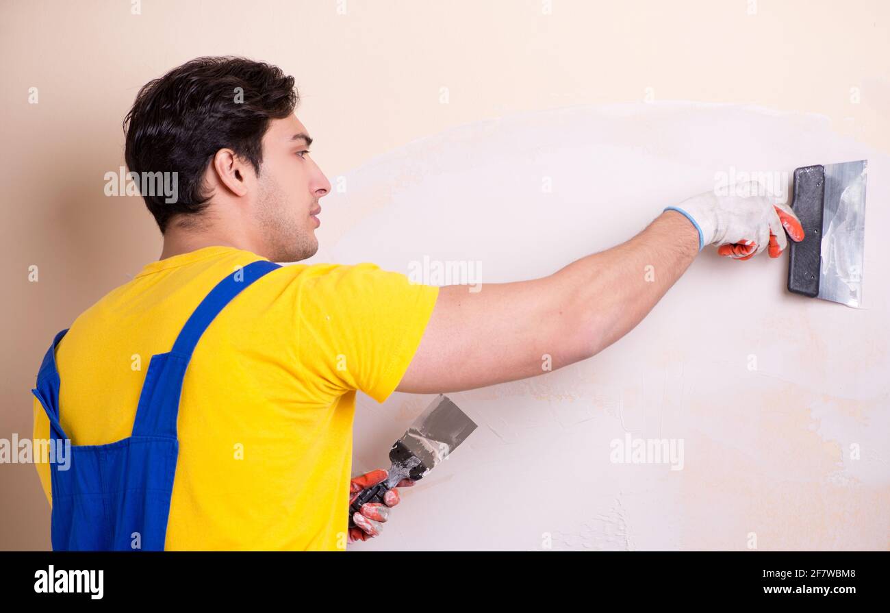 The young contractor employee applying plaster on wall Stock Photo