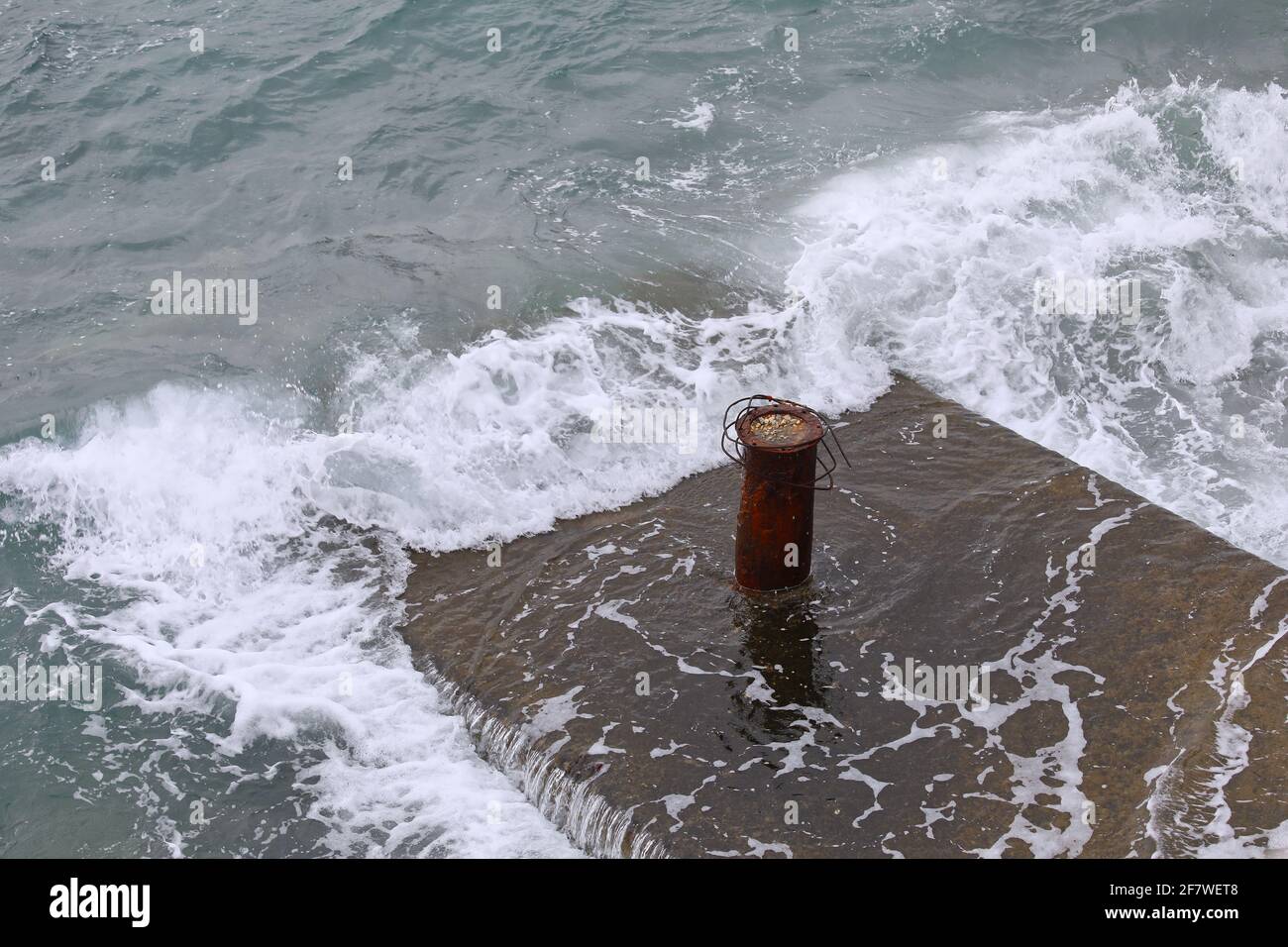 Dock Cleat On A Cement Platform.  Copy Space. Sea waves crashing platform. Stock Image Stock Photo