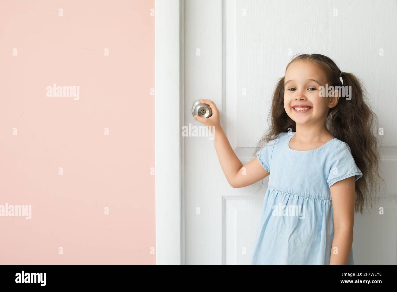 Cute little girl standing near closed door Stock Photo