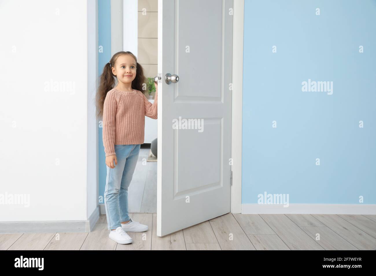 Cute little girl standing in doorway Stock Photo - Alamy