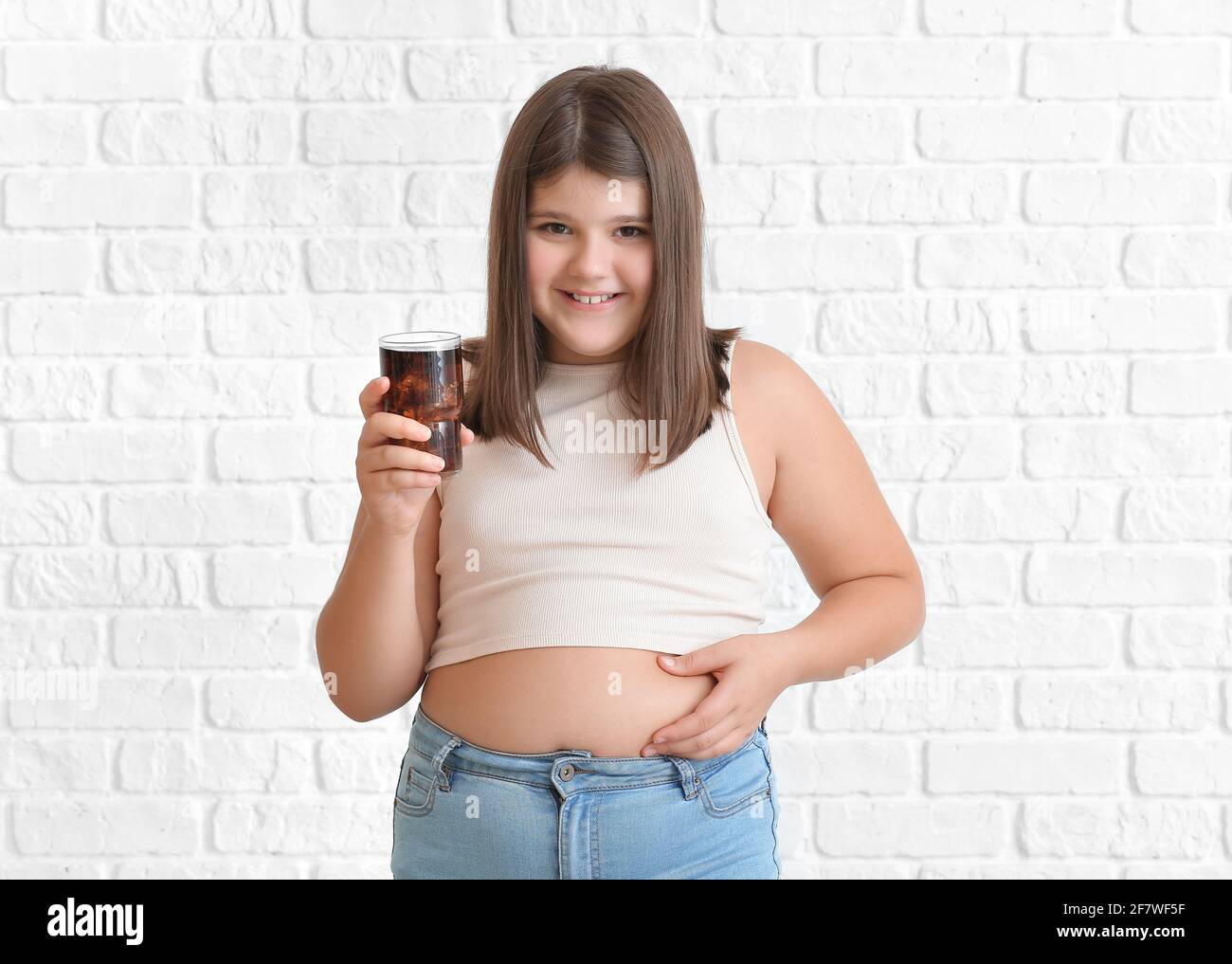 Gorda nina  Overweight girl with glass of unhealthy soda drink on white brick  background Stock Photo - Alamy