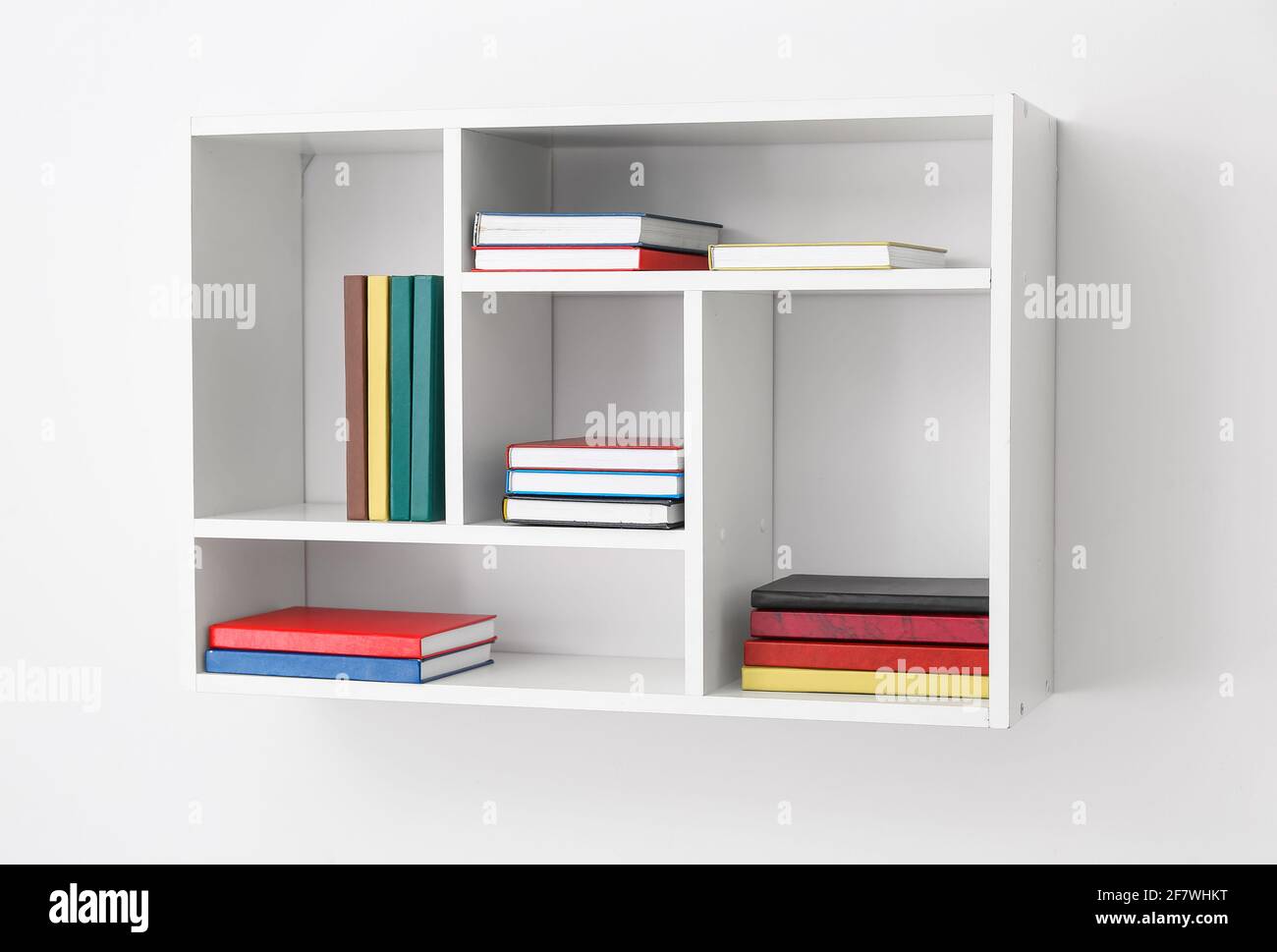 Shelf with books hanging on light wall Stock Photo - Alamy