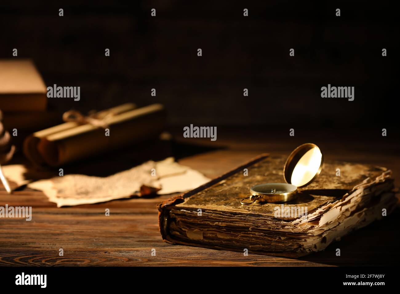 Old book with compass on table against dark background, closeup Stock Photo
