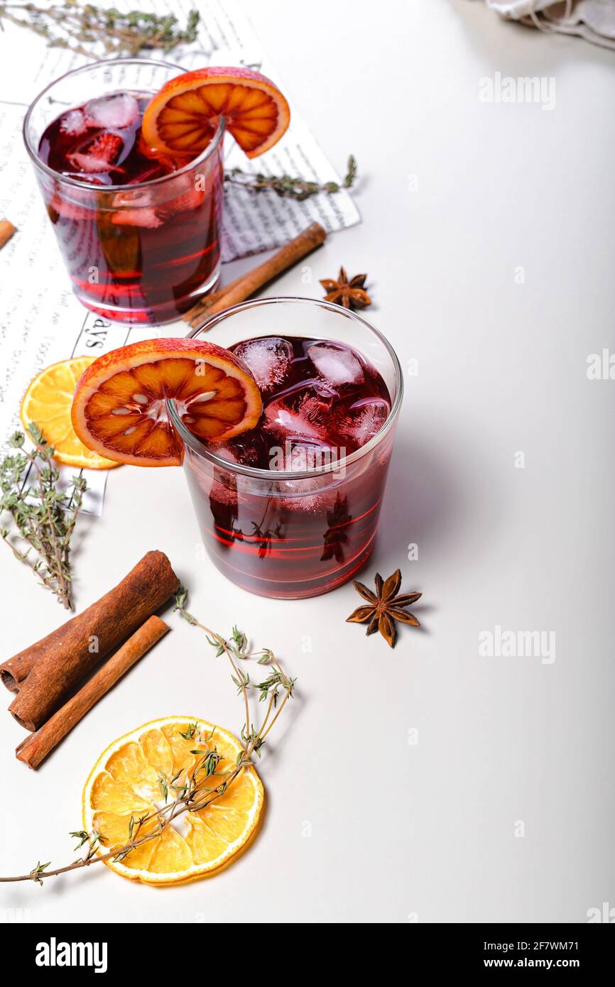 Cold mulled wine with cherry and bloody orange. Alcoholic beverage still life. Sicilian oranges, cinnamon sticks, oregano, anise and dried ginger. Lig Stock Photo
