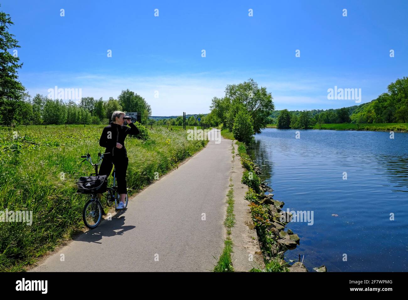 05.05.2020, Mülheim, Ruhrgebiet, Nordrhein-Westfalen, Deutschland - eine Radfahrerin auf einem Brompton-Faltrad beobachtet etwas durch ihr Fernglas an Stock Photo