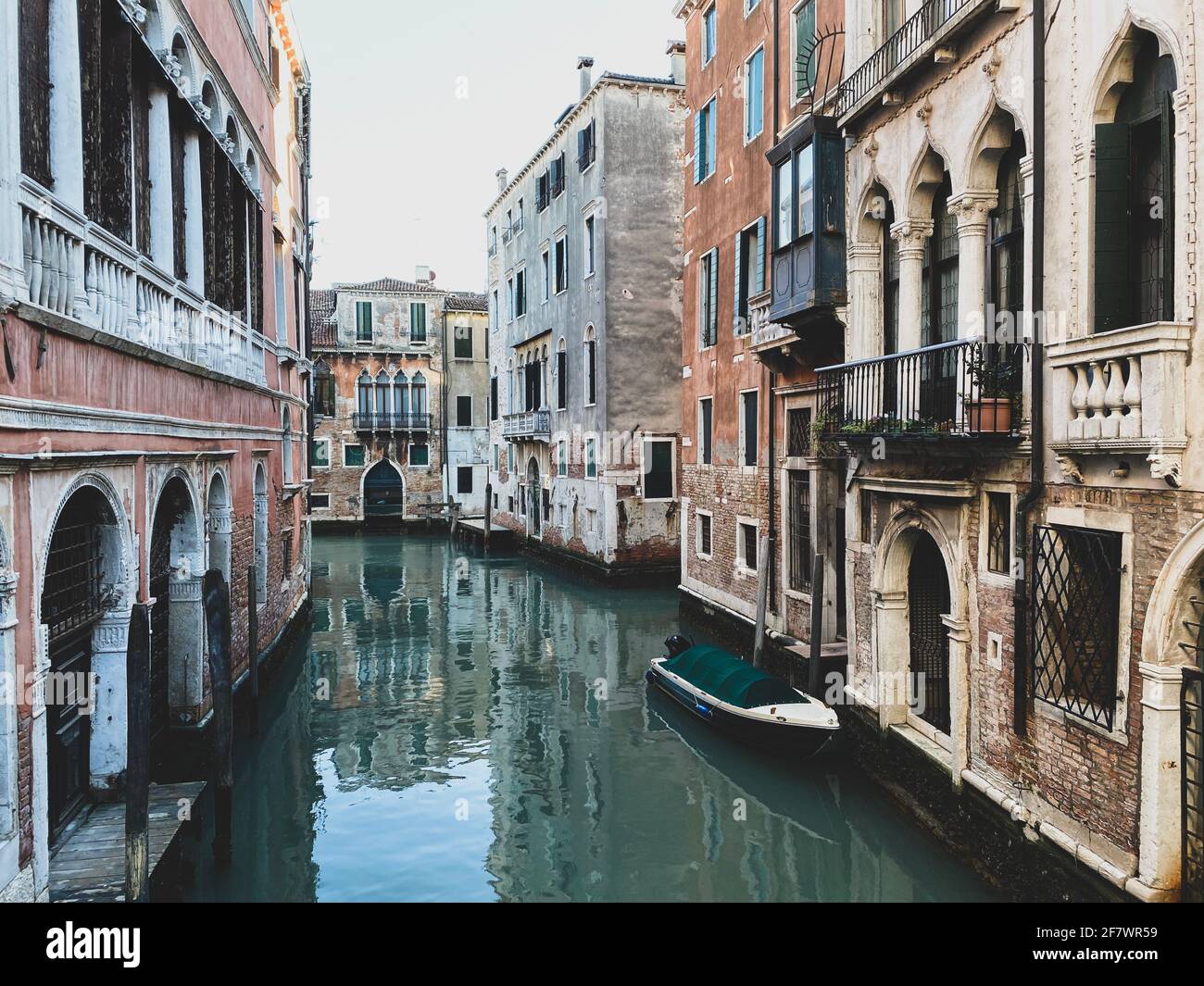 Small boat on a canal street in Venice with beautiful colorful houses ...