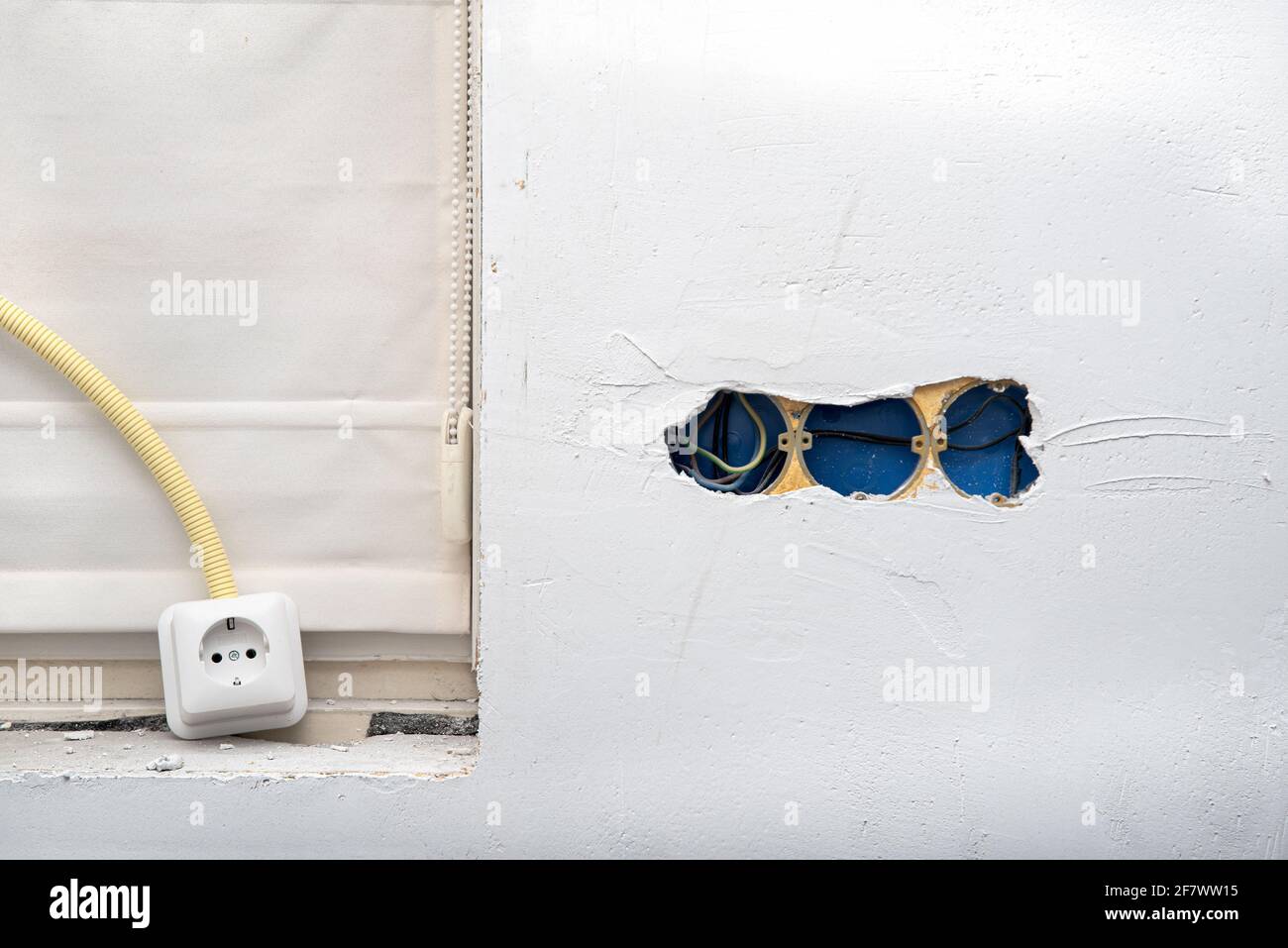 Electrical wire and opened junction box on plastering wall. Home renovation concept Stock Photo