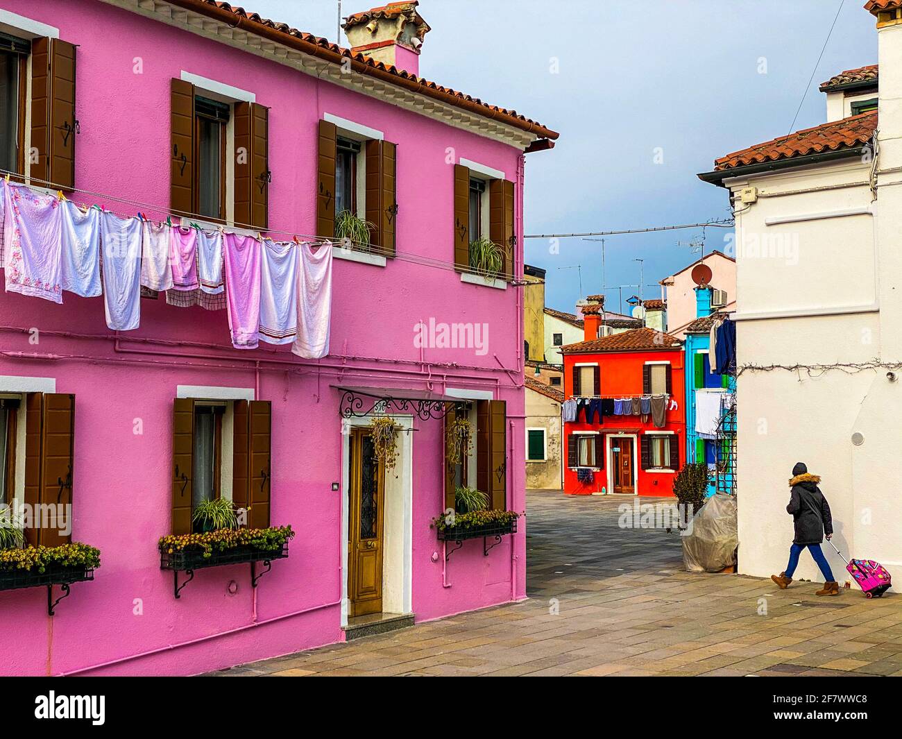 Person walking in the typical and very colorful streets of Burano. We see laundry being dried outside Stock Photo