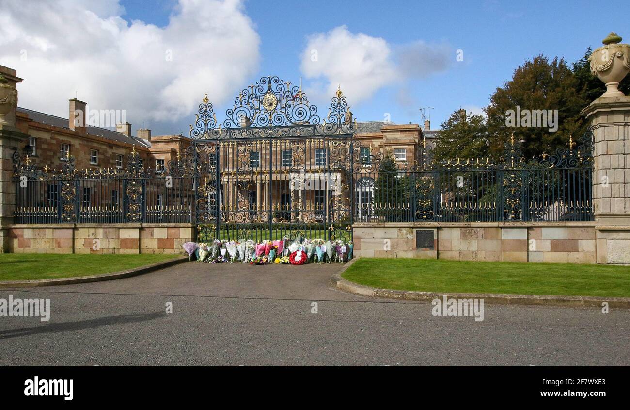 Hillsborough Castle, Hillsborough, County Down, Northern Ireland, UK. 10 April 2021. With the Union flag at half-mast, floral tributes have been left outside the gates of HM The Queen's official residence in Northern Ireland as the public mourn the loss of Prince Philip, Duke of Edinburgh, who died yesterday. Credit: David Hunter/Alamy Live News. Stock Photo