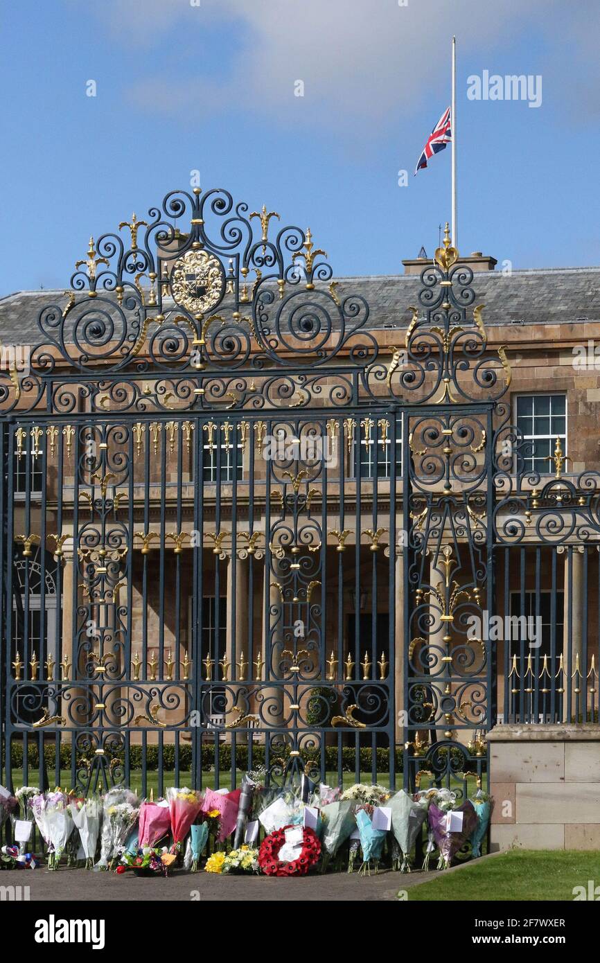 Hillsborough Castle, Hillsborough, County Down, Northern Ireland, UK. 10 April 2021. With the Union flag at half-mast, floral tributes have been left outside the gates of HM The Queen's official residence in Northern Ireland as the public mourn the loss of Prince Philip, Duke of Edinburgh, who died yesterday. Credit: David Hunter/Alamy Live News. Stock Photo
