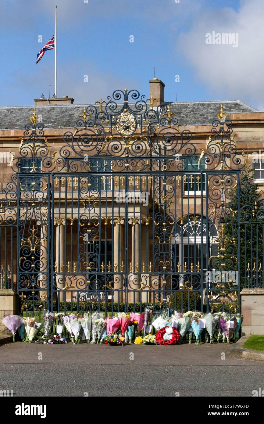Hillsborough Castle, Hillsborough, County Down, Northern Ireland, UK. 10 April 2021. With the Union flag at half-mast, floral tributes have been left outside the gates of HM The Queen's official residence in Northern Ireland as the public mourn the loss of Prince Philip, Duke of Edinburgh, who died yesterday. Credit: David Hunter/Alamy Live News. Stock Photo