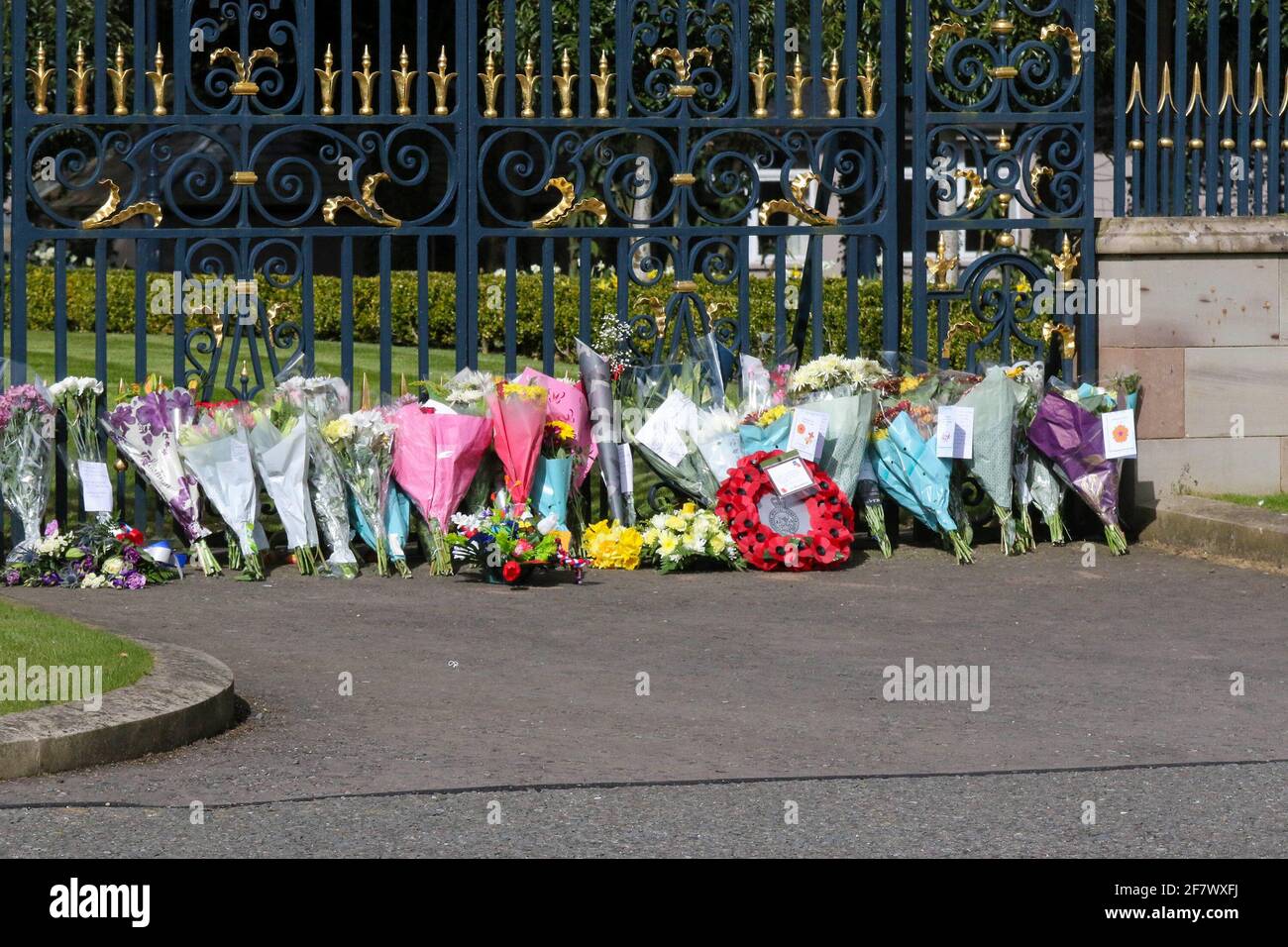Hillsborough Castle, Hillsborough, County Down, Northern Ireland, UK. 10 April 2021. With the Union flag at half-mast, floral tributes have been left outside the gates of HM The Queen's official residence in Northern Ireland as the public mourn the loss of Prince Philip, Duke of Edinburgh, who died yesterday. Credit: David Hunter/Alamy Live News. Stock Photo