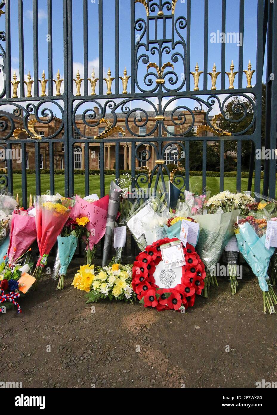 Hillsborough Castle, Hillsborough, County Down, Northern Ireland, UK. 10 April 2021. With the Union flag at half-mast, floral tributes have been left outside the gates of HM The Queen's official residence in Northern Ireland as the public mourn the loss of Prince Philip, Duke of Edinburgh, who died yesterday. Credit: David Hunter/Alamy Live News. Stock Photo
