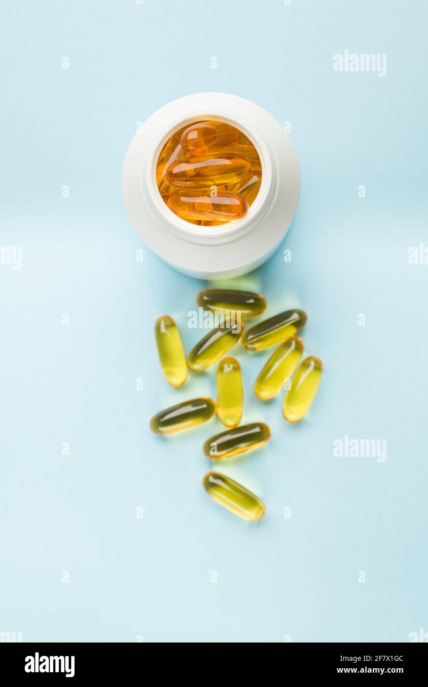Supplement gelatin pills on bottle on blue background. Stock Photo