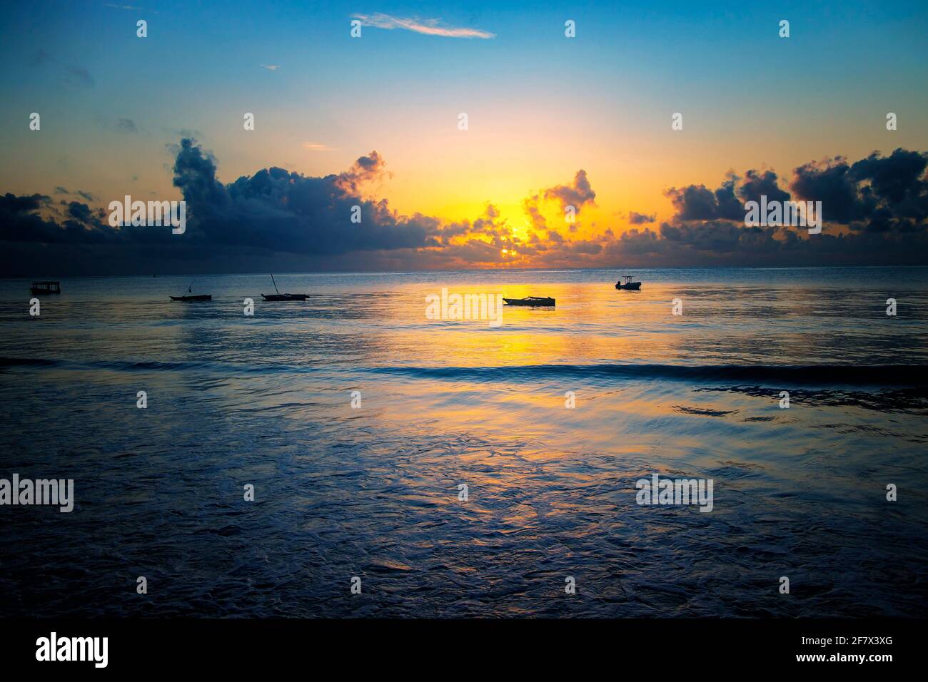 Sunrise over the sea at Diani beach near Mombasa, Kenya. There are small wooden boats on the water, Africa. Stock Photo