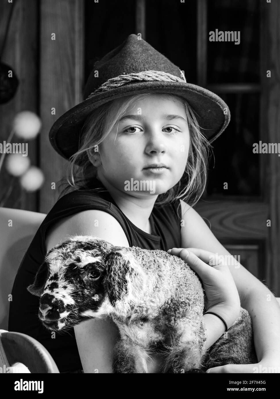 A girl in a shepherd's hat with a young newborn lamb in her arms Stock ...