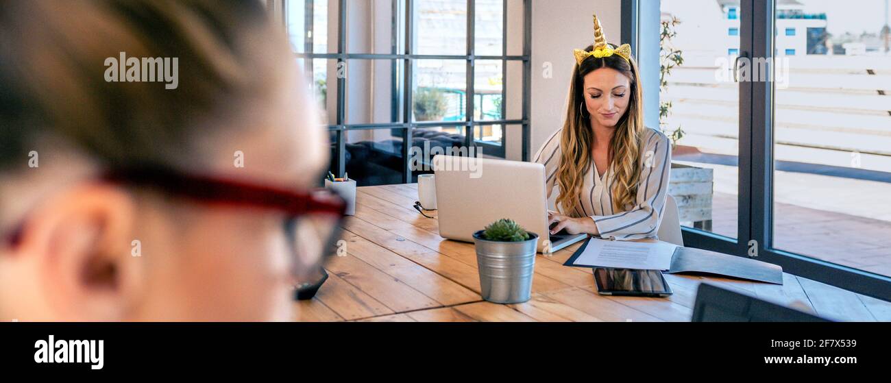 Businesswoman with unicorn headband working Stock Photo