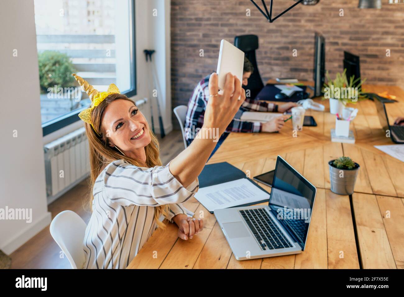 Business woman taking selfie with unicorn headband Stock Photo