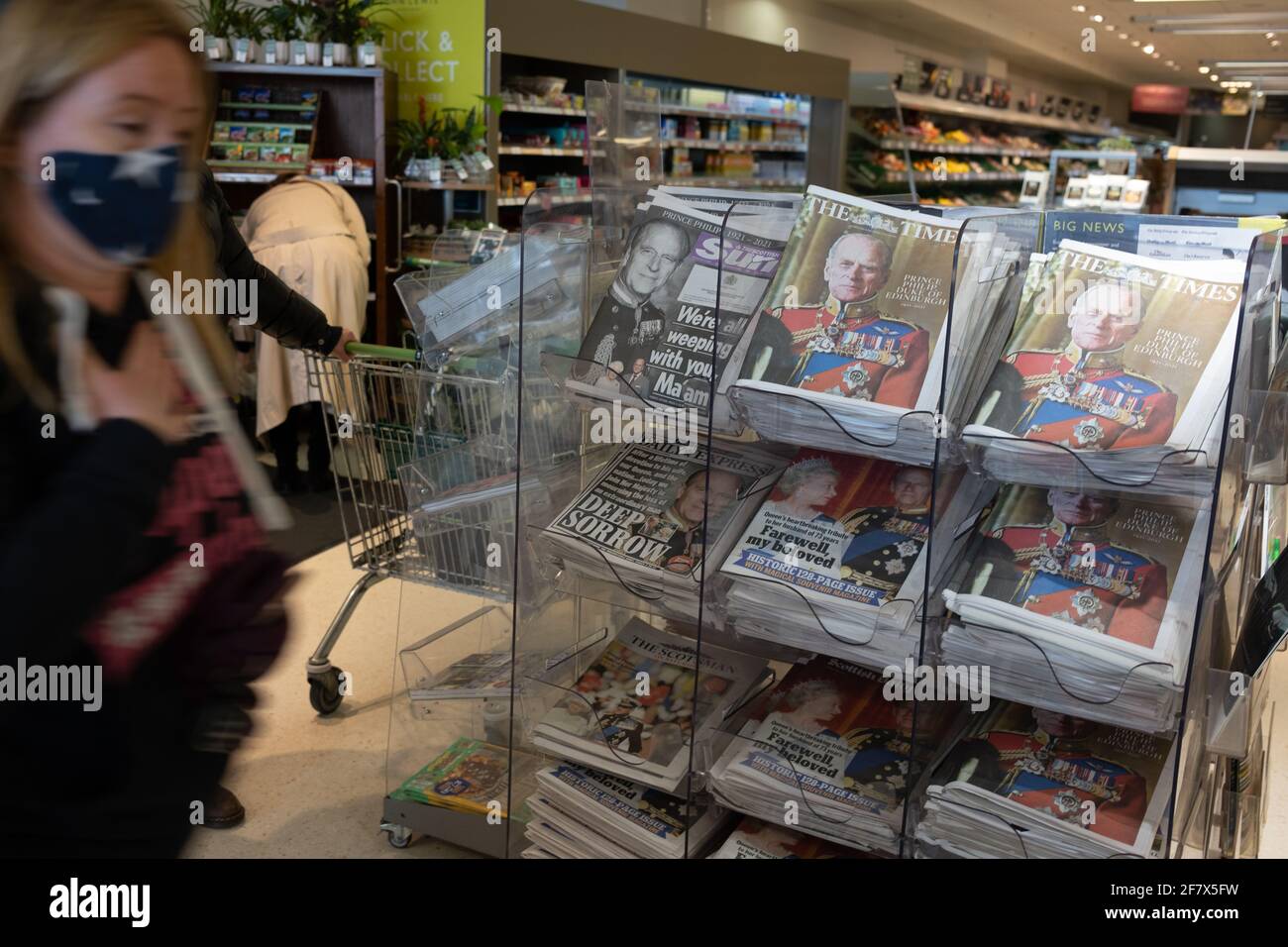 Glasgow, UK, 10th April 2021. Shoppers, wearing face masks due to the Covid-19 CoronaVirus health pandemic, pass by a display of newspapers announcing the death of His Royal Highness Prince Philip, Duke of Edinburgh, at the age of 99-years. Photo credit: Jeremy Sutton-Hibbert/Alamy Live News Stock Photo