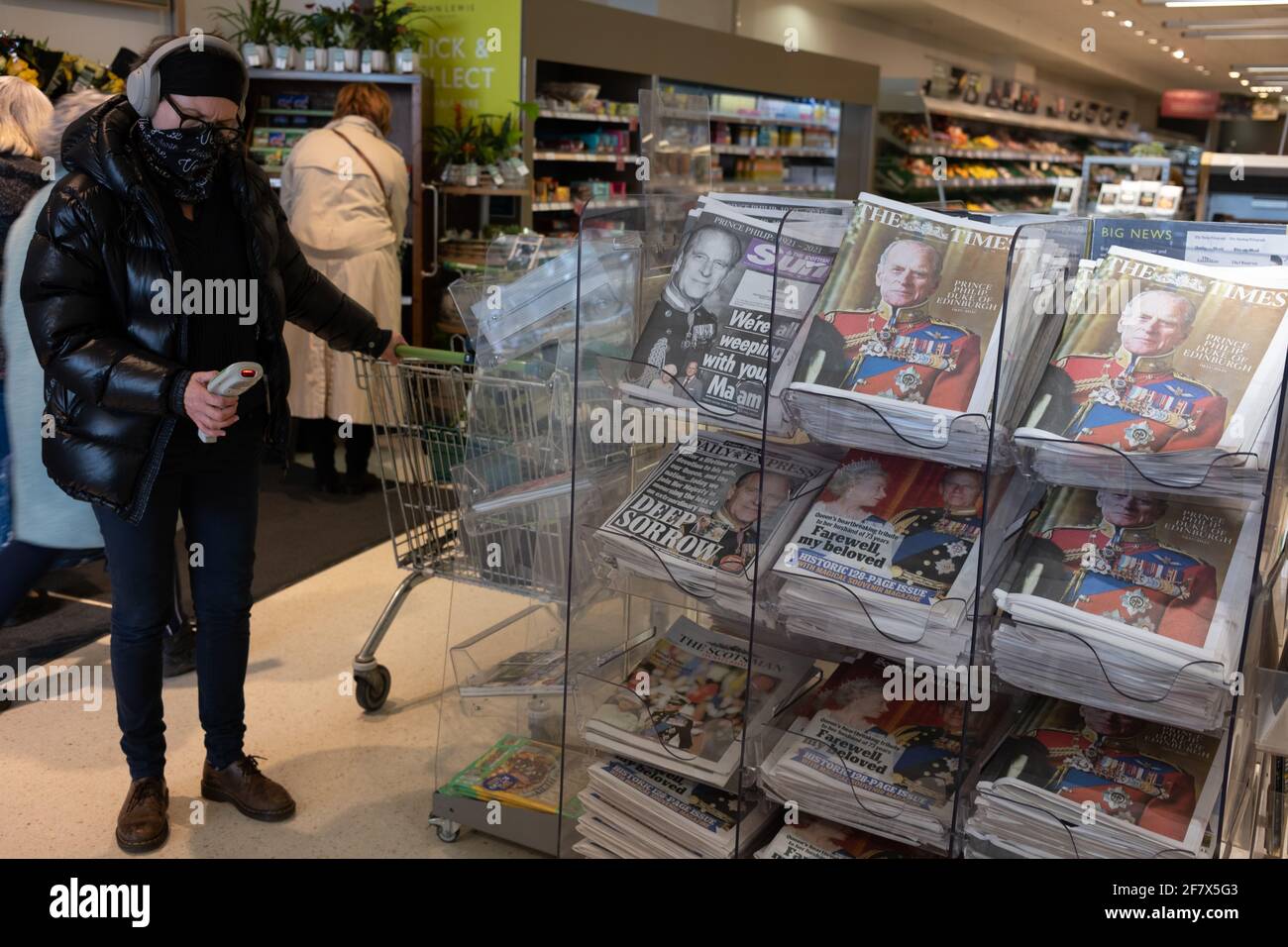 Glasgow, UK, 10th April 2021. Shoppers, wearing face masks due to the Covid-19 CoronaVirus health pandemic, pass by a display of newspapers announcing the death of His Royal Highness Prince Philip, Duke of Edinburgh, at the age of 99-years. Photo credit: Jeremy Sutton-Hibbert/Alamy Live News Stock Photo