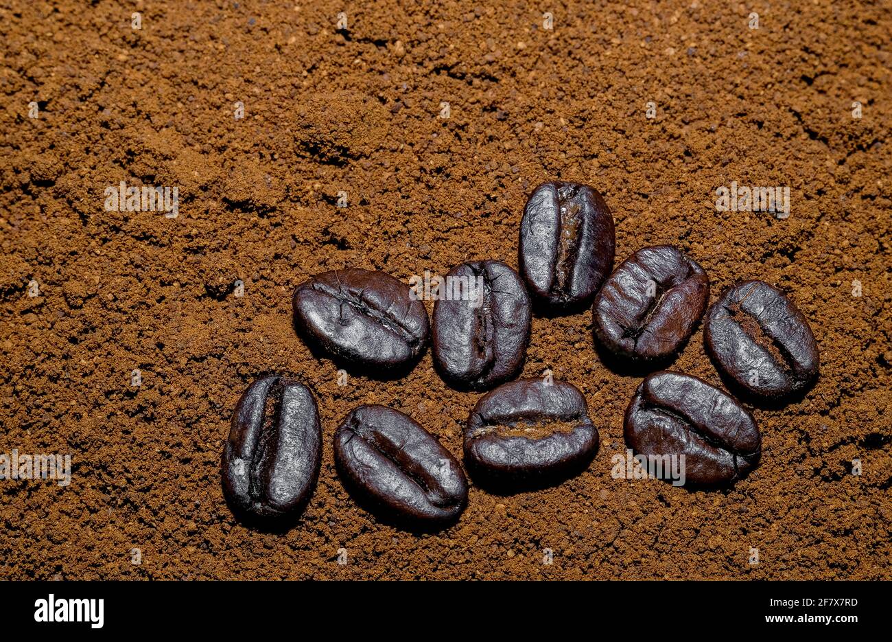 ground black coffee background with a few whole black coffee beans Stock Photo