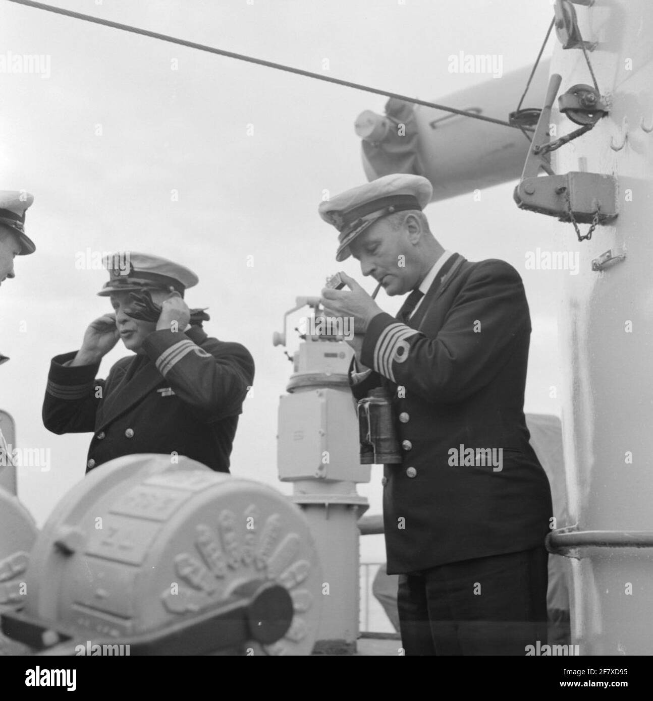 Adelborstenreizen 13 - 29 April, 10 - 16 June and 3 -31 July 1953. The commander of HR. Ms. Tromp, captain at sea c.w.th. Baron of Boetzelaer (right) sticks up his pipe, standing at the engine camereleg on the bridge of from HR Ms. Tromp (1948-1954). Is part of Object series AVDKM 530003 up to 530023 and 530051 to 530053. Stock Photo