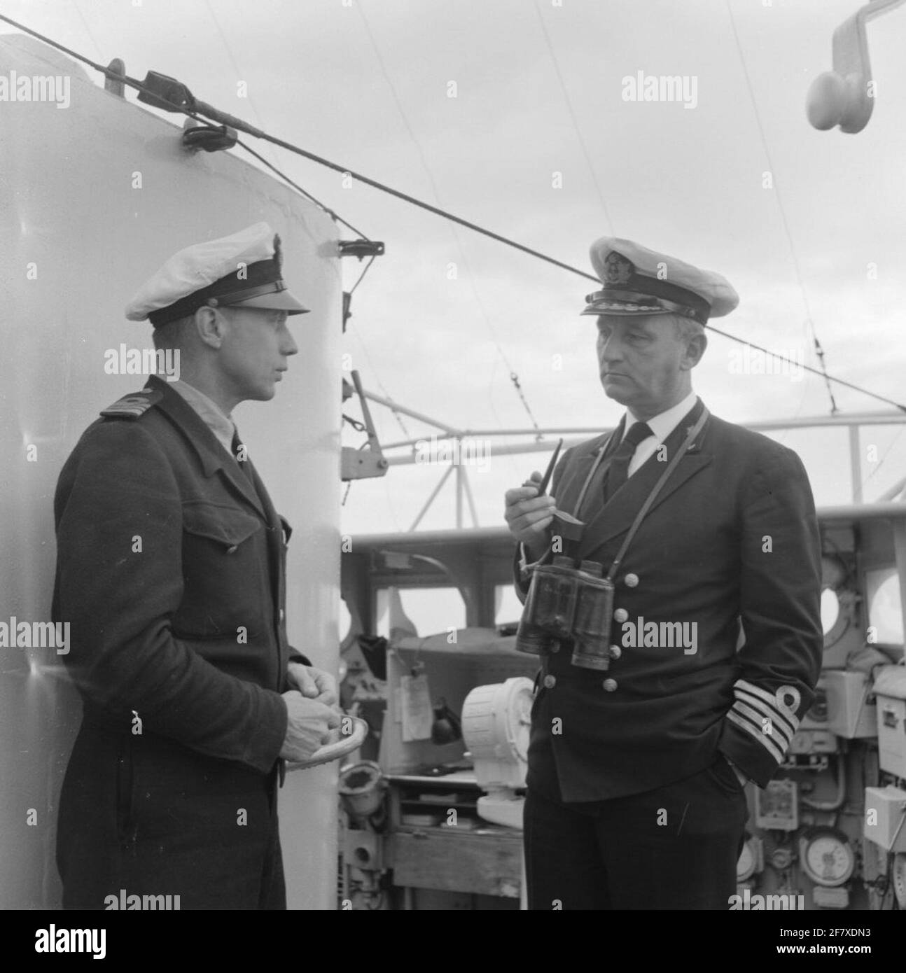 Adelborstenreizen 13 - 29 April, 10 - 16 June and 3 -31 July 1953. The commander of HR. Ms. Tromp, captain at sea c.w.th. Baron van Boetzelaer (right), in conversation with lieutenant at sea J. Ptasnik on the bridge of from HR Ms. Tromp (1948-1954). Is part of Object series AVDKM 530003 up to 530023 and 530051 to 530053. Stock Photo