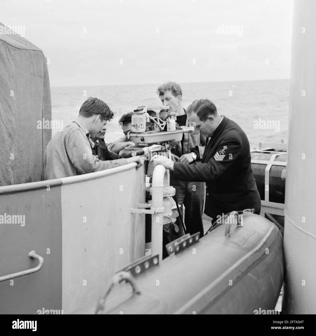 Fishing inspection in the North Sea with the frigate of predator class Hr.Ms. Wolf (F 817) (1954-1984) (EX-USS PCE 1607). On board the wolf, the outboard engine of the dinghy / rubber boat is checked by, among other things, a Sergeant-Machinist (SGTMACH). Stock Photo