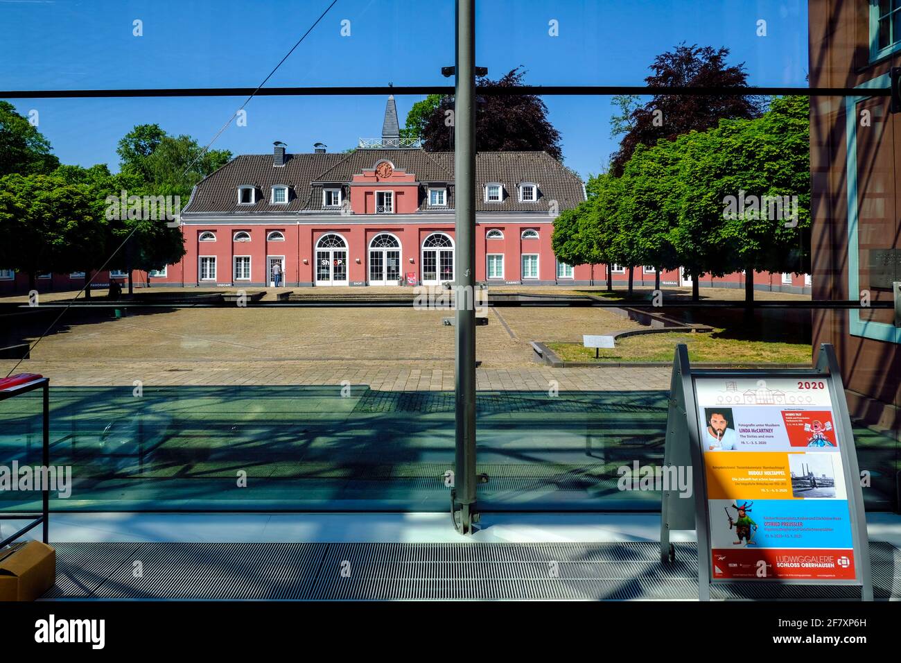07.05.2020, Oberhausen, Nordrhein-Westfalen, Deutschland - Blick durch die Glasfassade des Hauptgebaeudes auf das Kleine Schloss in der Anlage von Sch Stock Photo