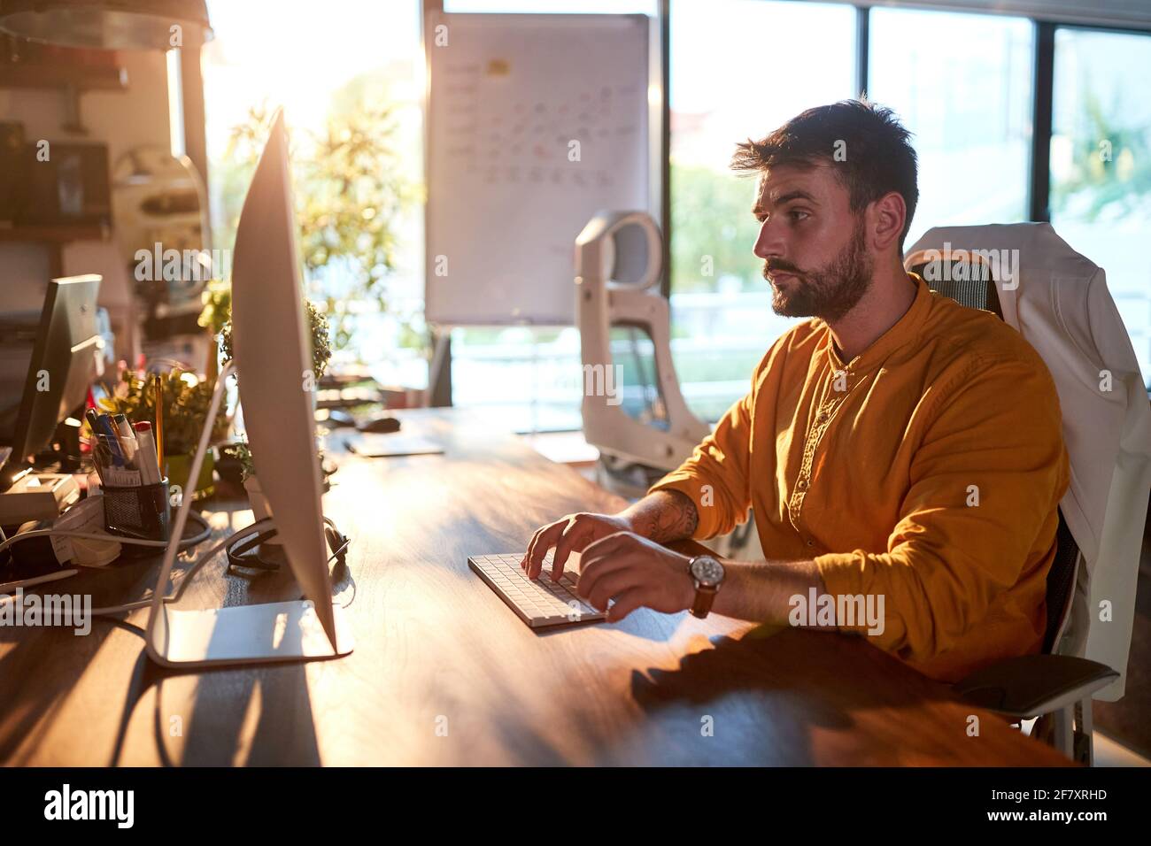 A young male office worker is focused on the job at the desk in a working atmosphere in the office. Business, office, job Stock Photo