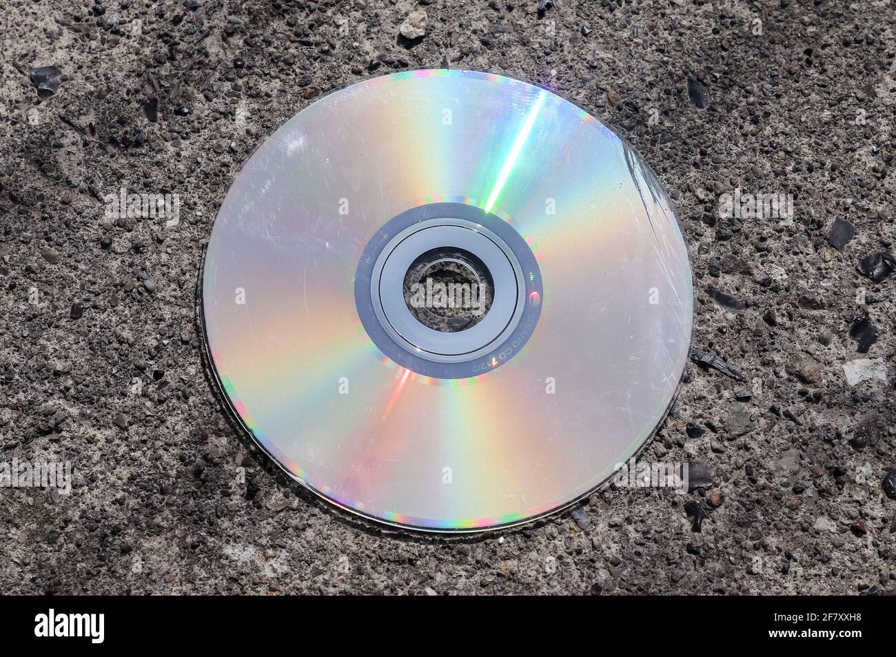 Old used compact disc on an asphalt road Stock Photo