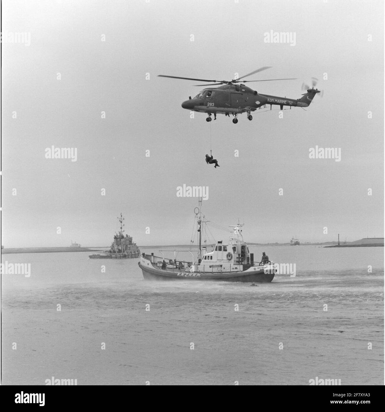 Exercise Person transport From a floating platform by the Westland SH-14D Navy Lynx Helicopter with registration 283 (1981-approx. 2012) in collaboration with the bright rescue boat Suzanna (1968-1998) of the Royal North and South Holland Redding Company (Knzhrm) In May 1990. On the background a marine trail from the Delta Tug 2750 type (1987-). Stock Photo