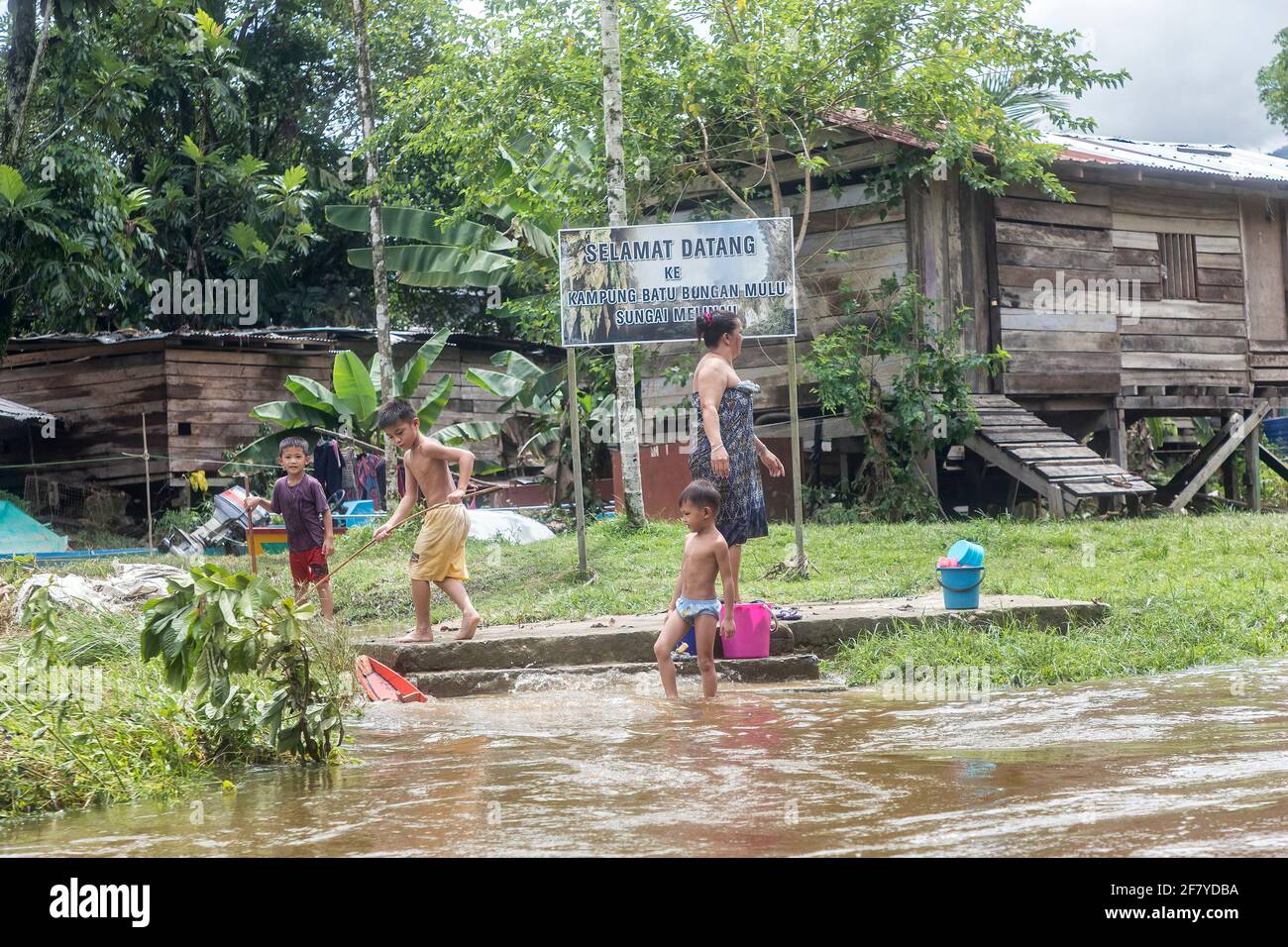 Children playing at edge of river, Selamat Datang, village, Mulu, Malaysia Stock Photo