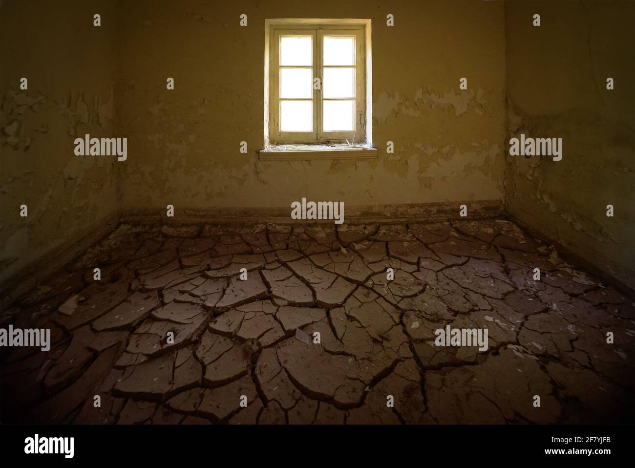 Abandoned house interior. Room with cracked clay on the floor and peeling yellow paint on walls Stock Photo