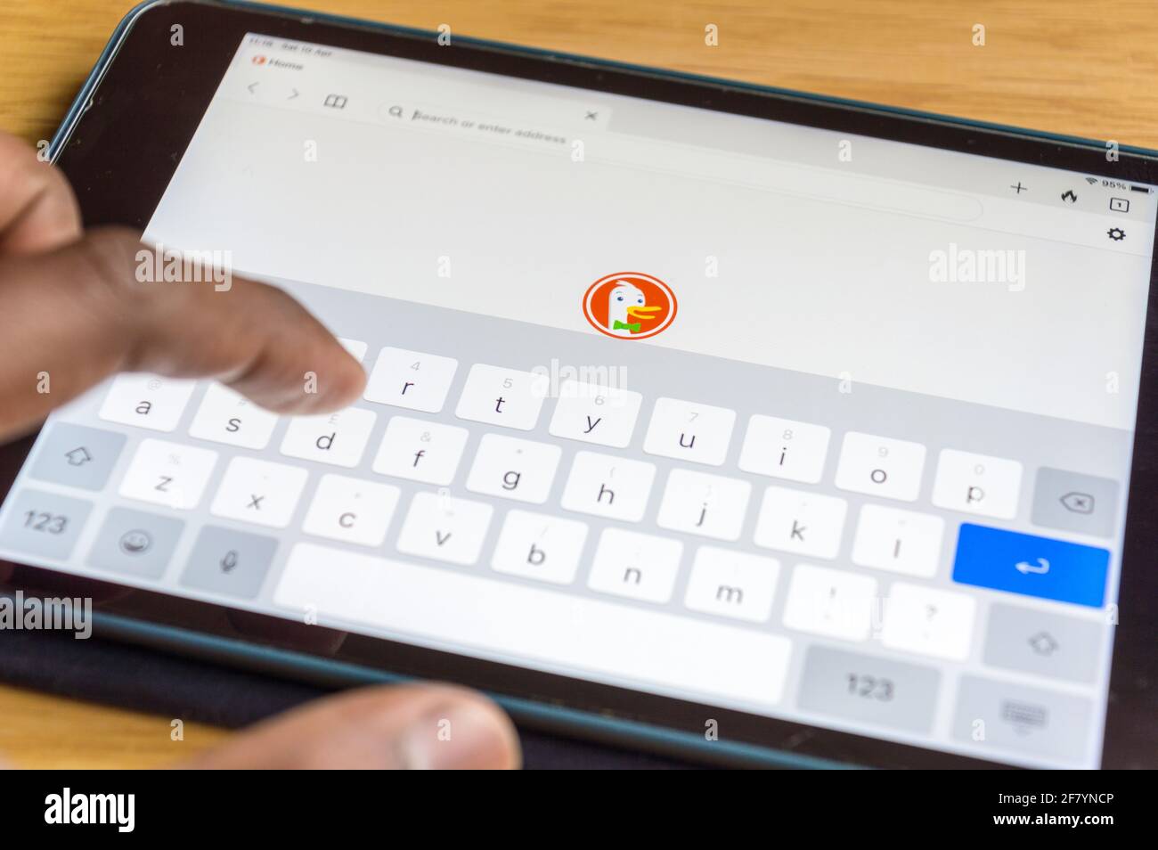 Adult male typing on ipad keypad on Duck duck go interner browser Stock Photo
