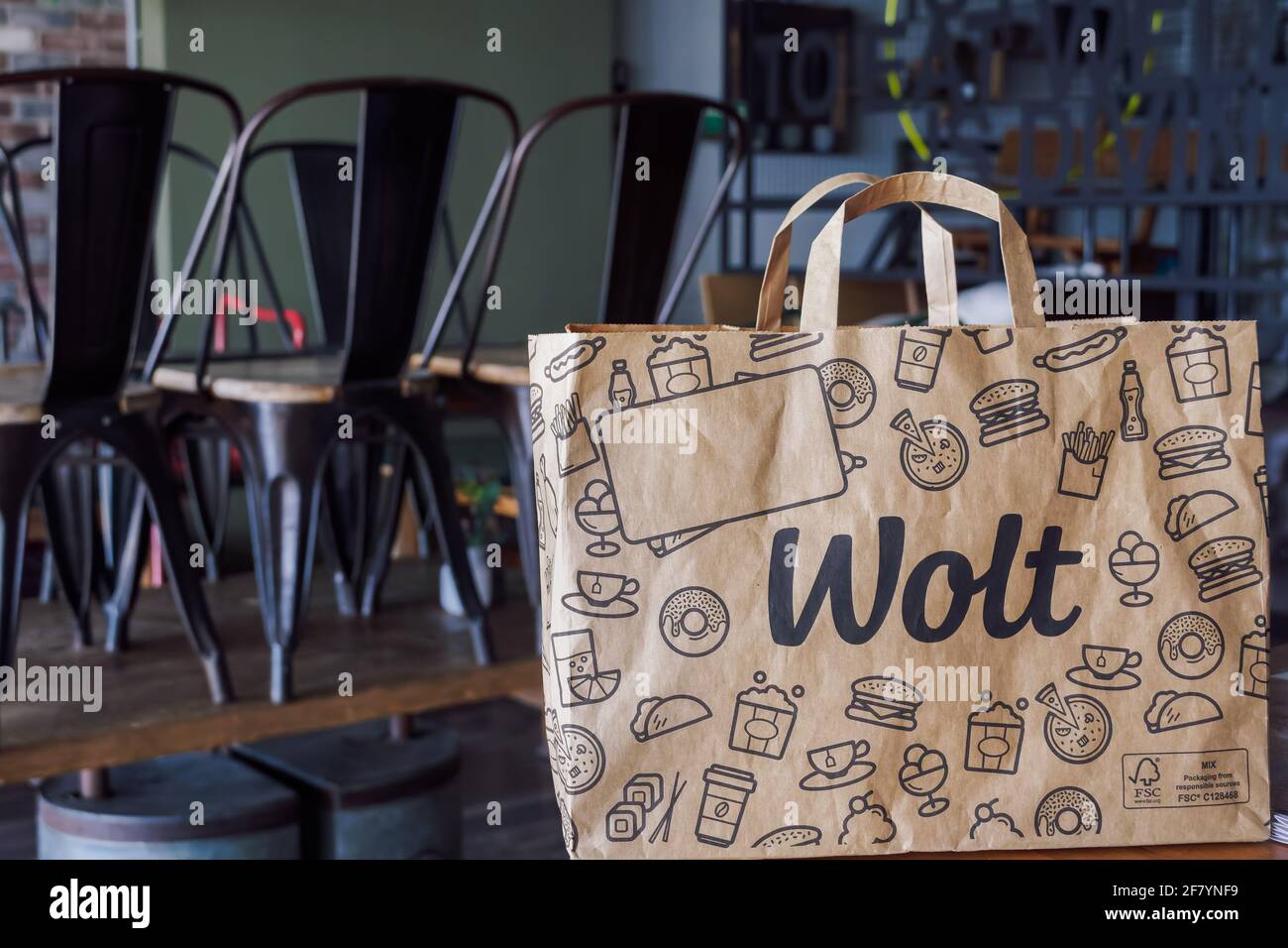 Wolt food delivery bag with company logo, on restaurant. Finish company paper bag with handle, used by platform courier partners. Stock Photo