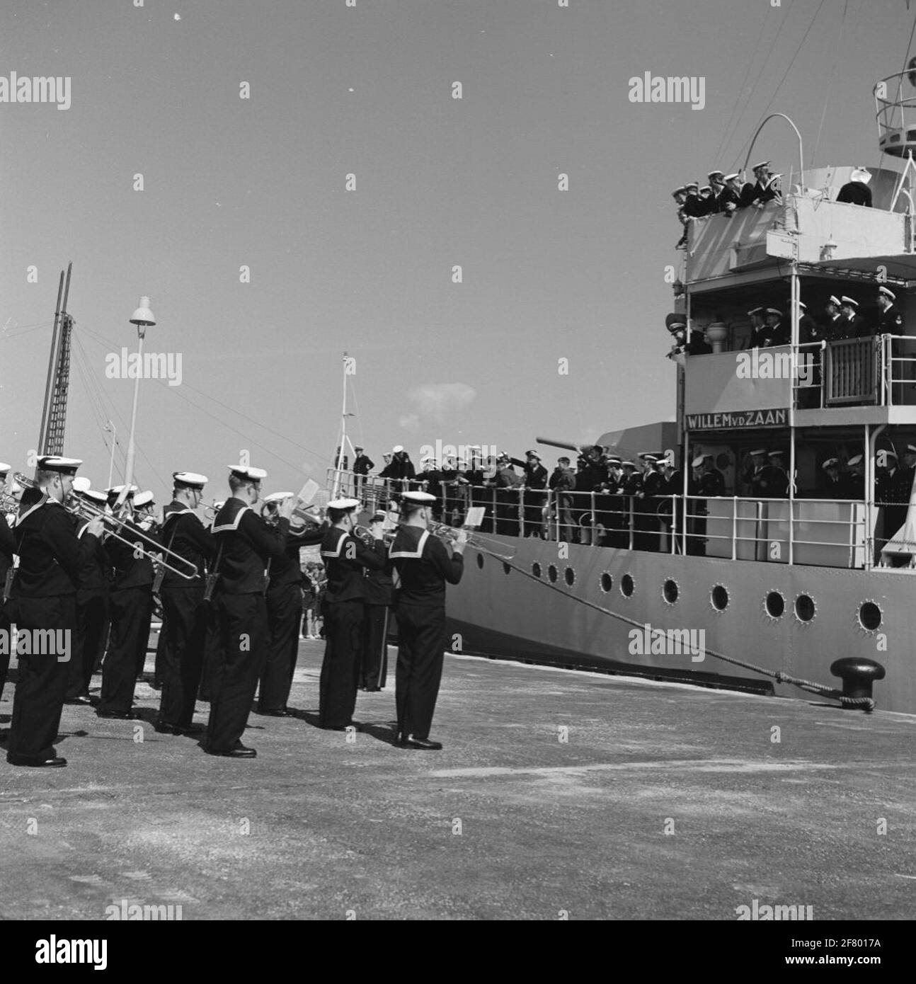 The Frigate Hr.Ms. Willem van der Zaan (F 824) returns with musical accompaniment from the west in the port of Den Helder, mid-1956. Please note the 'lead traitor' (figurehead of very likely the frigate of war Zr.Ms. Alphen, CA. 1778) To the sender. Stock Photo
