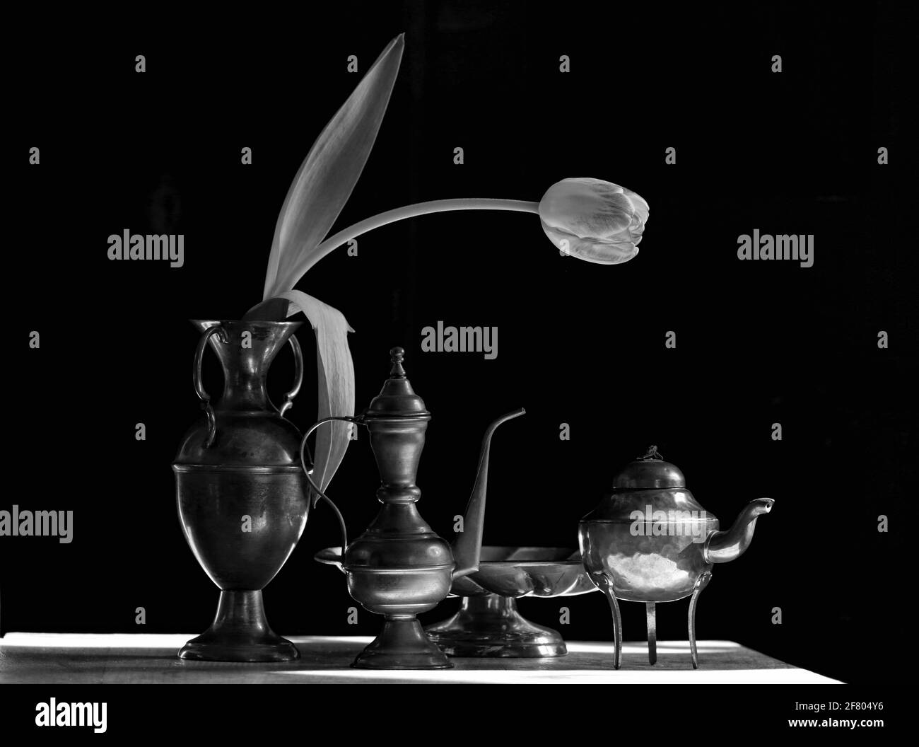 One tulip with brass items on a table in day light with black background Stock Photo