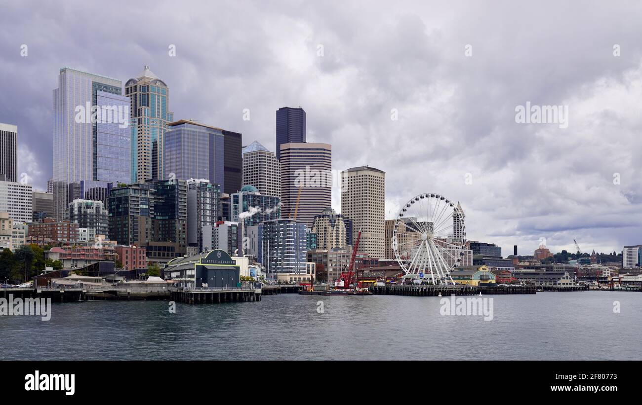 Skyscraper and The Great Wheel at Pier 57 of Seattle, Washington, USA, under cloudy sky. Stock Photo