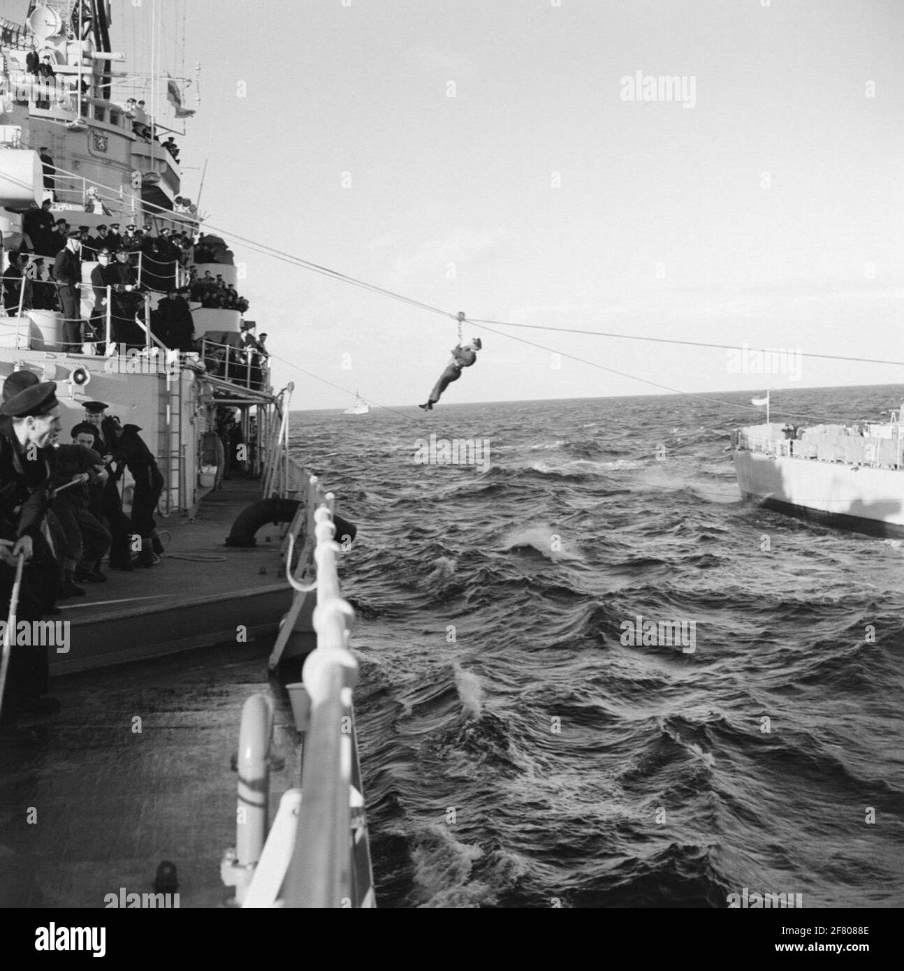 The surrendering of light burden and people between cruiser Hr.Ms. The Seven Provinces (C802, Left) and the Frigate Hr.Ms. Of Ewijck (F 808, right) during a practice period (1956-12 to 1956-03-29) from Practenmaleel 5.On the background the torpedo boat hunter Hr.Ms. Evertsen (D 802). Stock Photo