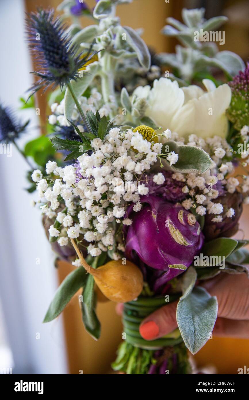 purple and white bouquet of flowers being held by a woman indoor Stock Photo