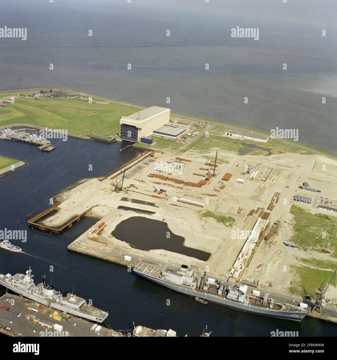 Aerial recording of the new construction of the computer facilities Center on the new port in Den Helder in May 1989. In the foreground an S-FREGAT (1978-2003) and (just a part visible) the GW frigate Hr.Ms. De Ruyter (F 806, 1976-2001). On the other side of the water the supply ship Hr.Ms. Zuiderkruis (A 832,! 975-2012). Stock Photo