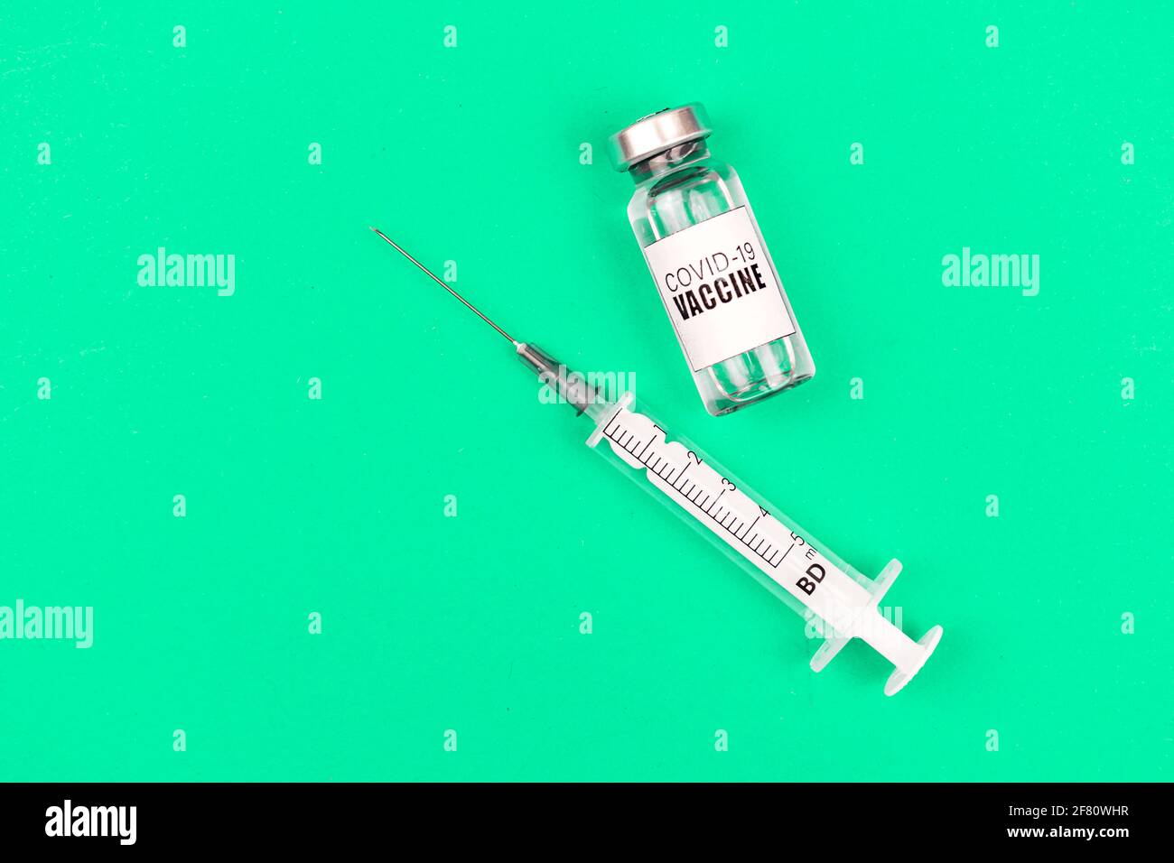 Vial with coronavirus vaccine and medical syringe on a green background ...