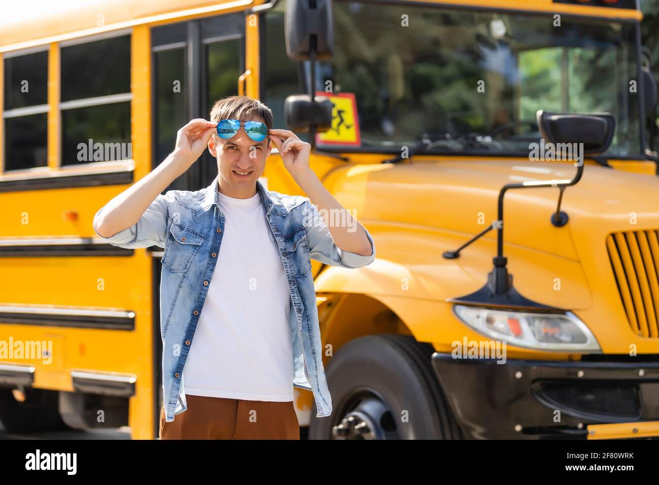 Portrait of smiling teacher near school bus Stock Photo - Alamy