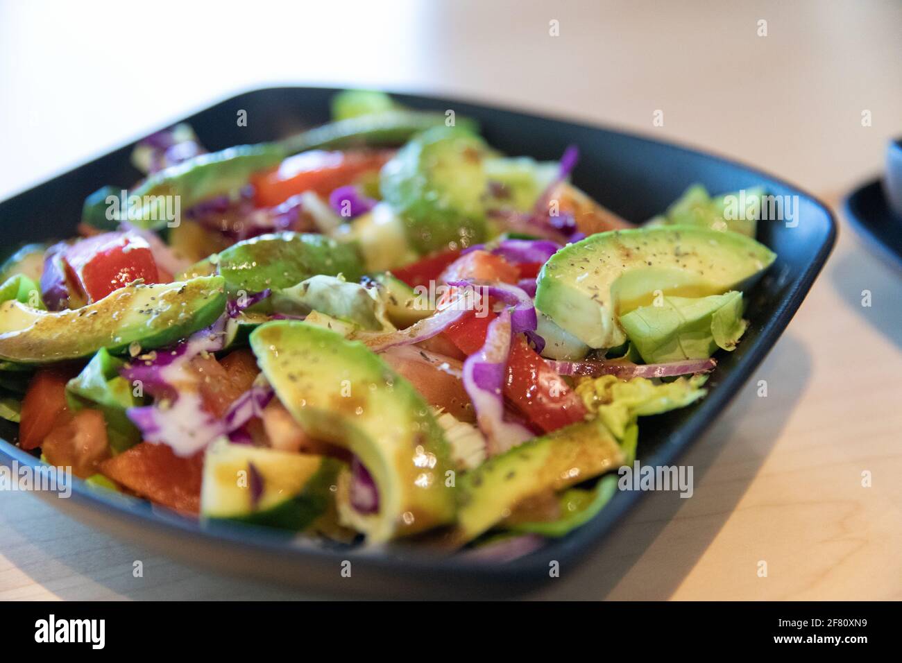 Fresh avocado salad with onions and other veggies and dressing in a square plate Stock Photo