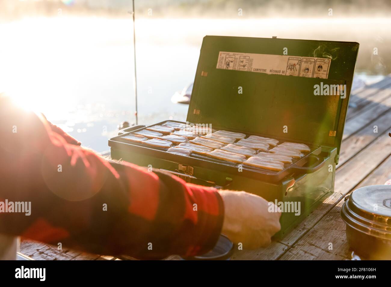 Man's hand adjusting the fire on a portable stove on a sunrise Stock Photo
