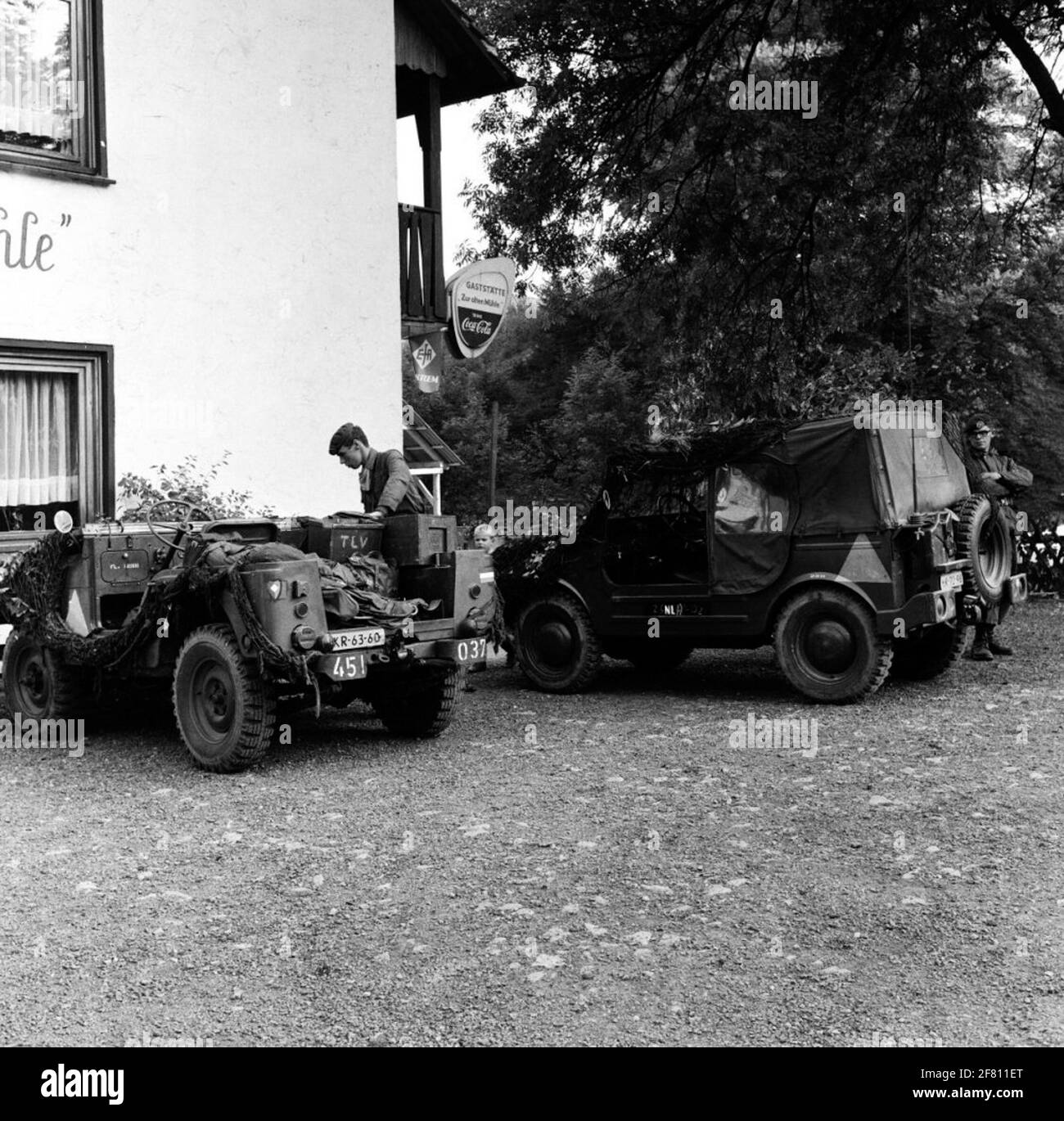Two soldiers from the Royal Netherlands Army at a Nekaf M38A1 (left) parked next to an inn and a DKW Munga during exercise Eternal Triangle. Stock Photo