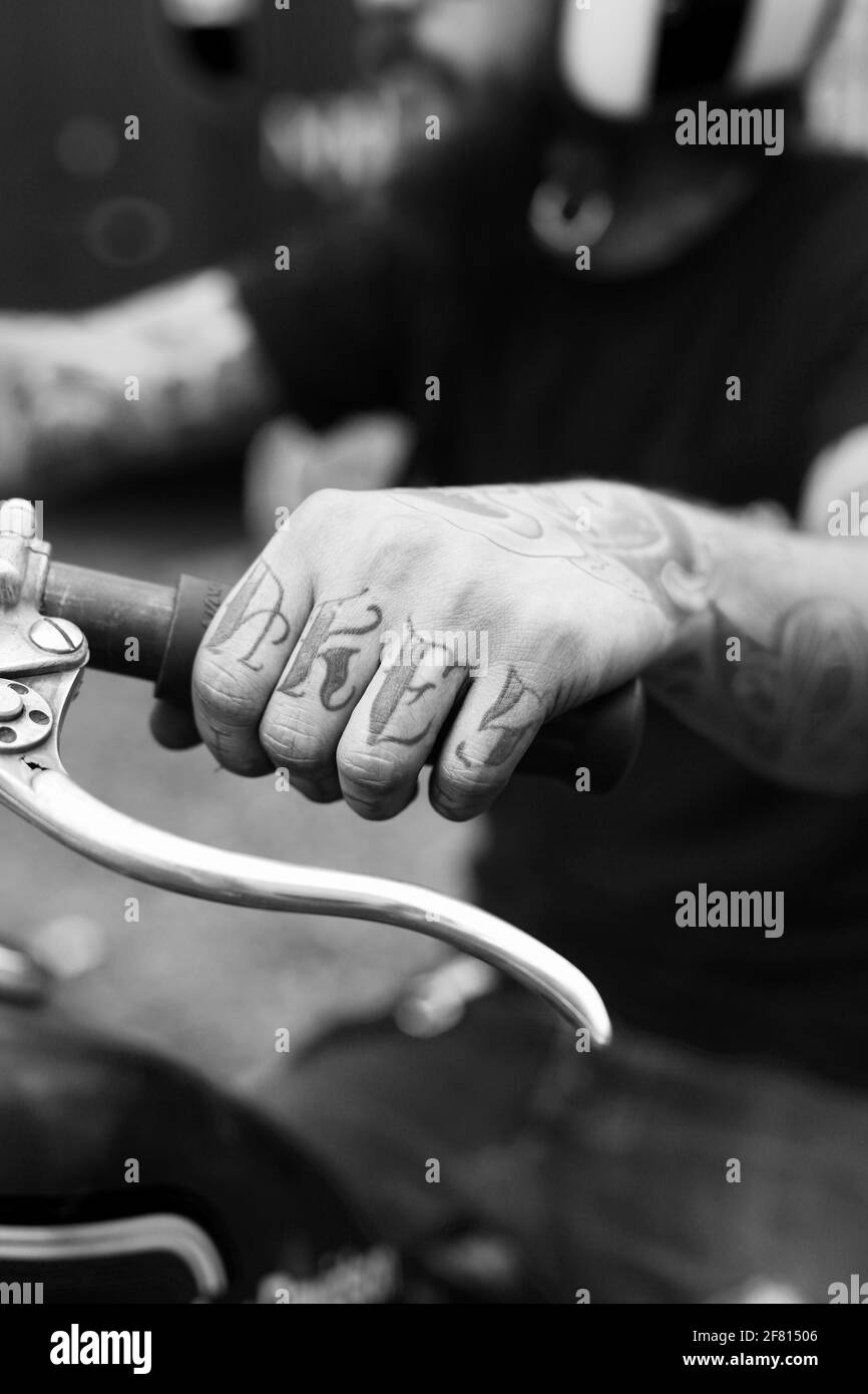 A man hold on to a motorcycle handle, showing off his tattoo.Hands close up. Stock Photo