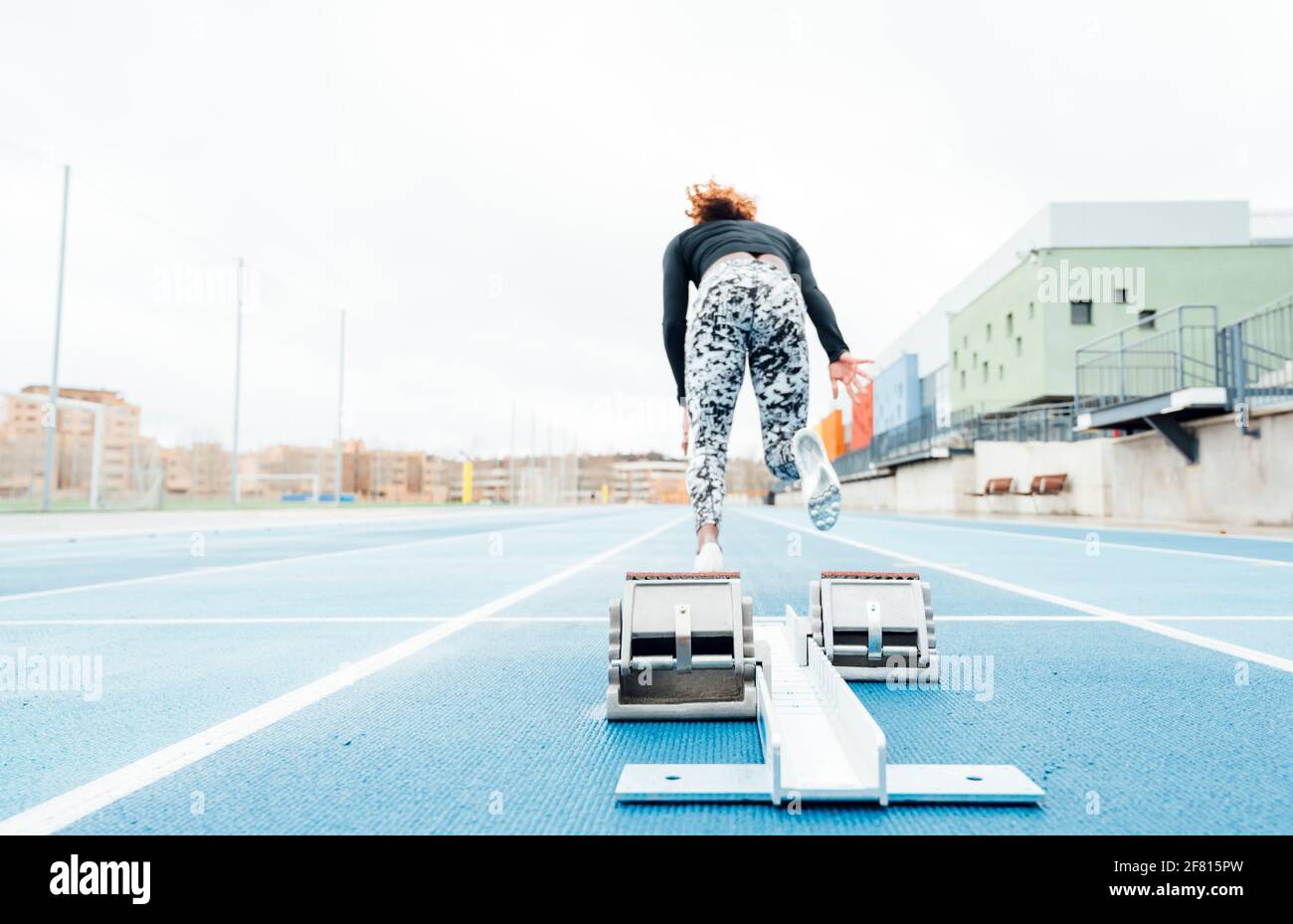 Back view of young strong sportswoman beginning to run fast from